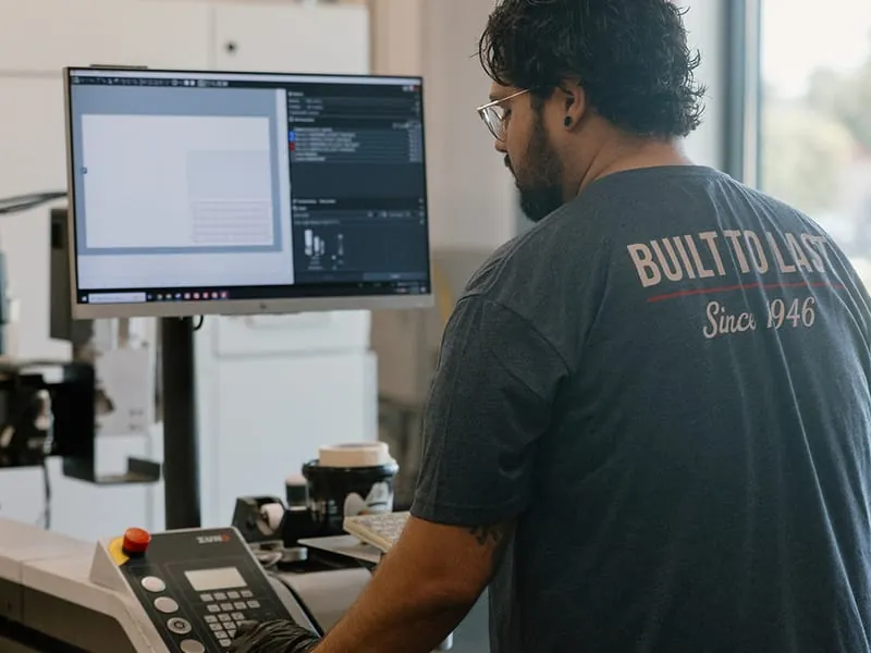 An operator at the cutting table wearing a Built to Last, Since 1946 shirt