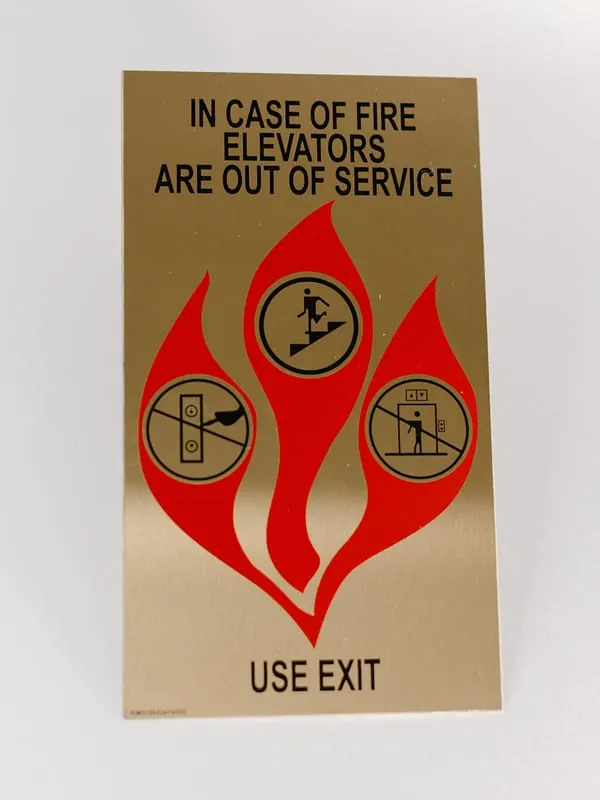 A brass elevator safety plate reading In Case of Fire, Elevators Are Out of Service