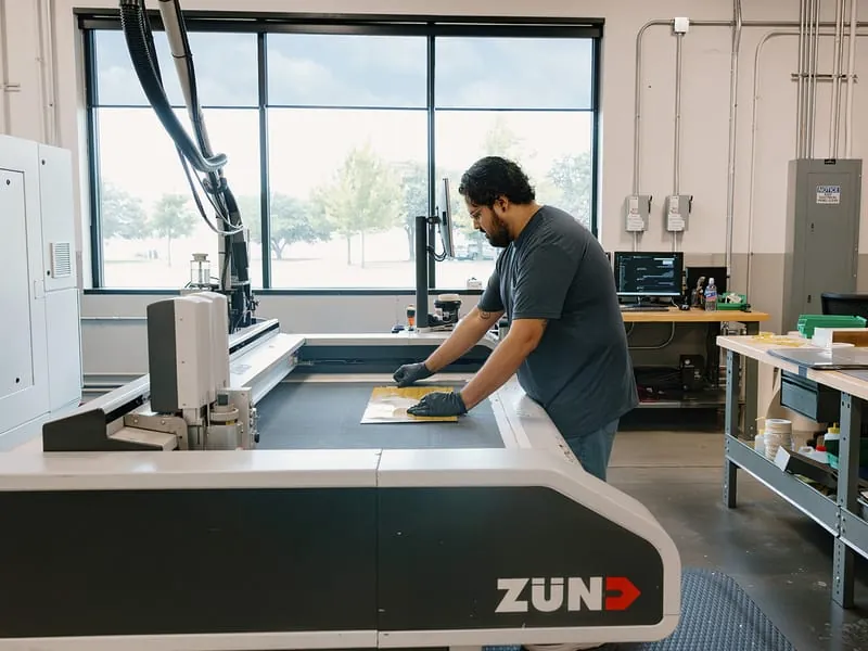 An operator smoothing a sheet onto the knife cutter bed