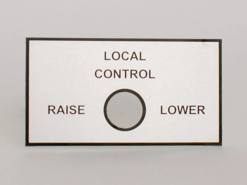 A Metalphoto local control plate reading Raise and Lower around a switch cutout