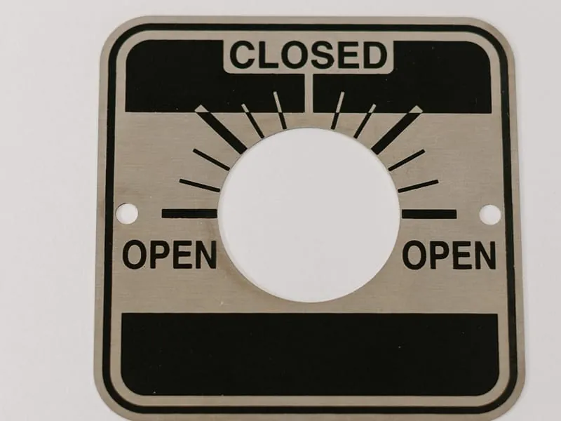A stainless steel valve position indicator plate reading Closed and Open