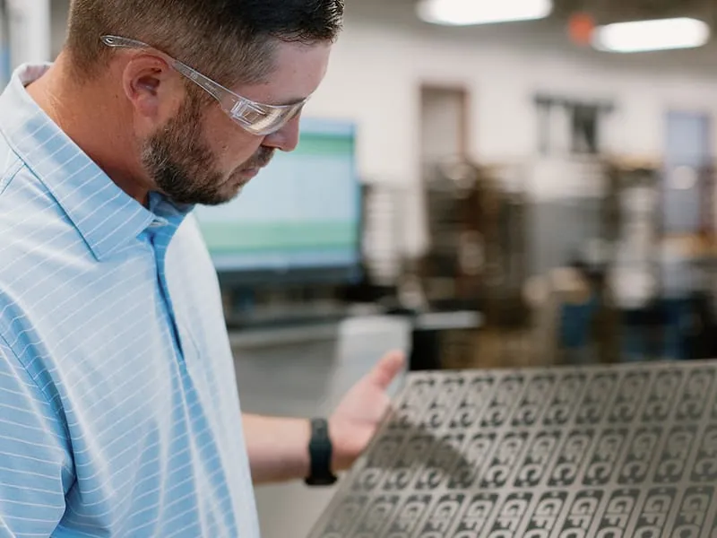 Inspecting a freshly etched stainless steel sheet of nameplates