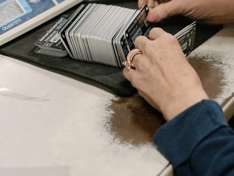 Hands fanning a banded stack of finished tags beside a counting scale